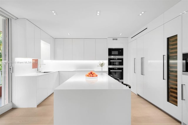 kitchen featuring white cabinetry, stainless steel appliances, light hardwood / wood-style flooring, and a kitchen island