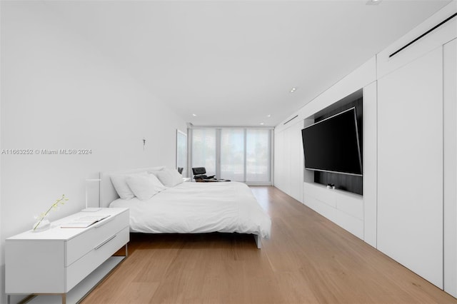 bedroom with light wood-type flooring and floor to ceiling windows