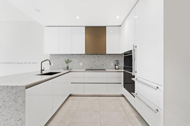 kitchen with decorative backsplash, white cabinetry, light tile patterned flooring, black appliances, and sink