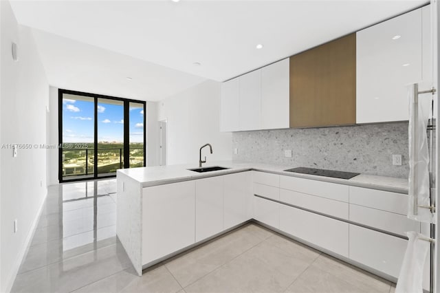 kitchen with a peninsula, decorative backsplash, floor to ceiling windows, black electric cooktop, and modern cabinets