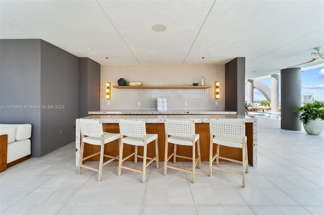 kitchen with a kitchen breakfast bar, light tile patterned floors, and tasteful backsplash