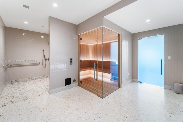 interior space with recessed lighting, speckled floor, visible vents, and a tile shower