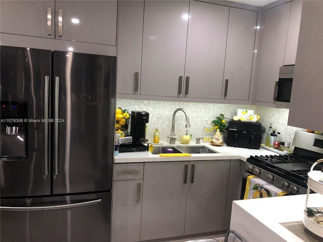 kitchen featuring gray cabinets, sink, appliances with stainless steel finishes, and tasteful backsplash