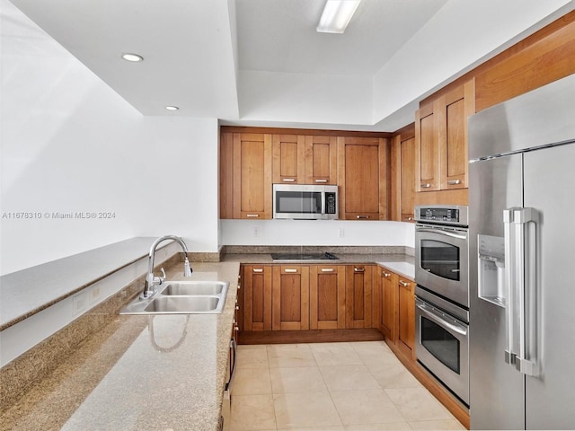 kitchen featuring light tile patterned floors, stainless steel appliances, light stone countertops, and sink