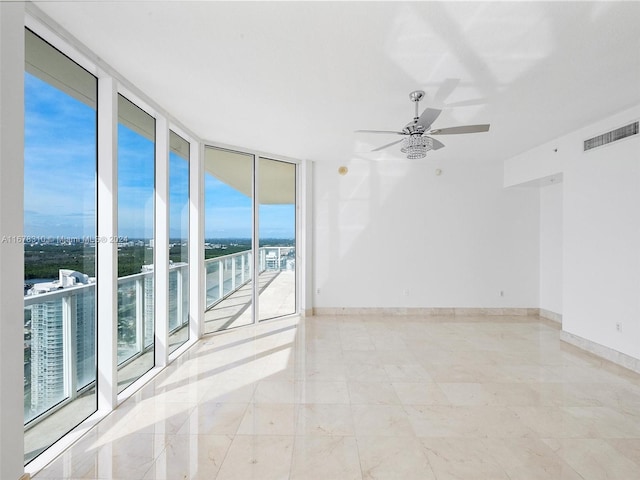 tiled empty room featuring a water view and a wall of windows