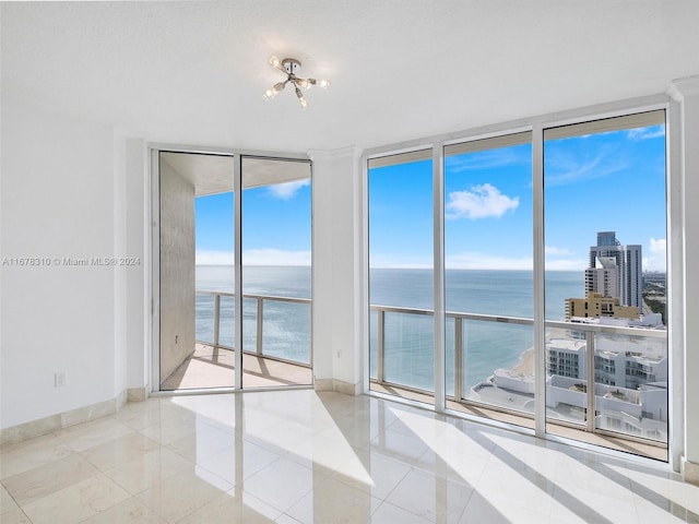 tiled empty room featuring a water view and floor to ceiling windows