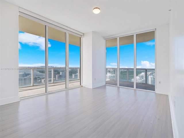 empty room featuring a wall of windows and hardwood / wood-style floors