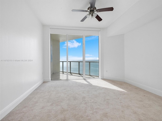 spare room with light carpet, a water view, and ceiling fan