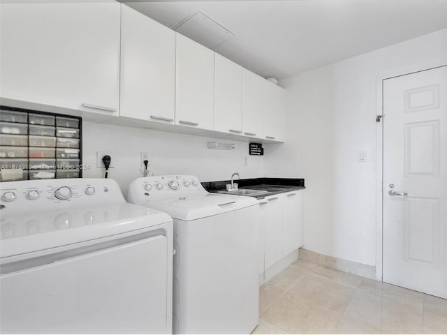 clothes washing area with sink, washing machine and dryer, light tile patterned floors, and cabinets