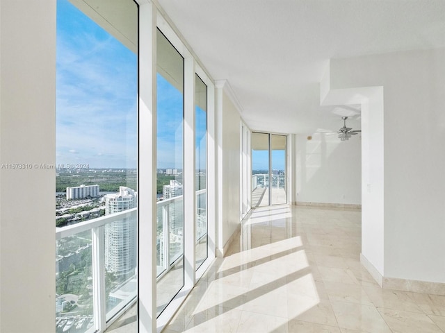 empty room with expansive windows, a healthy amount of sunlight, and ceiling fan