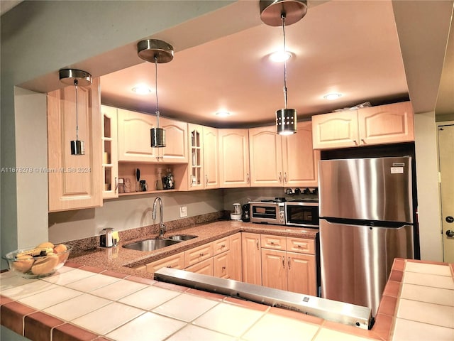 kitchen featuring tile countertops, sink, appliances with stainless steel finishes, and decorative light fixtures