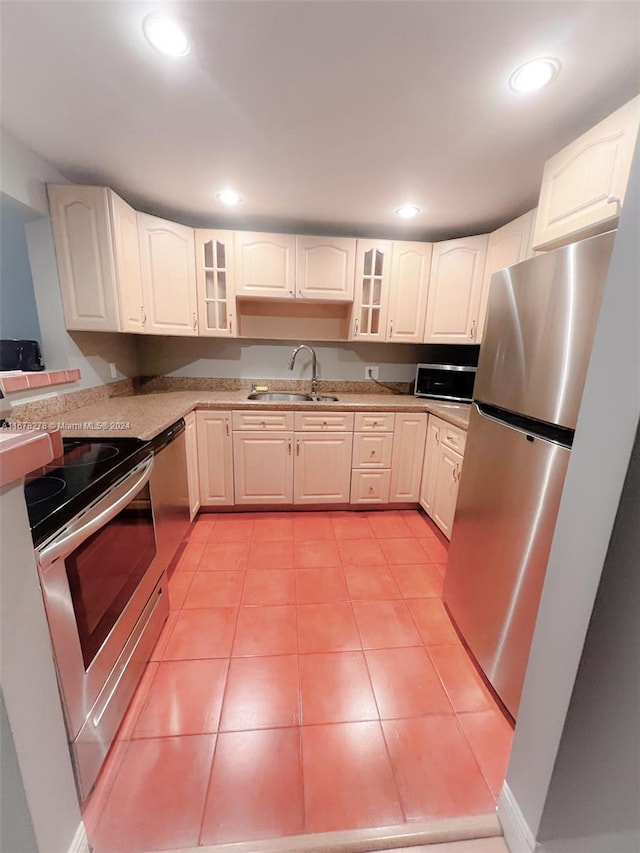 kitchen with sink, white cabinets, stainless steel appliances, and light tile patterned floors