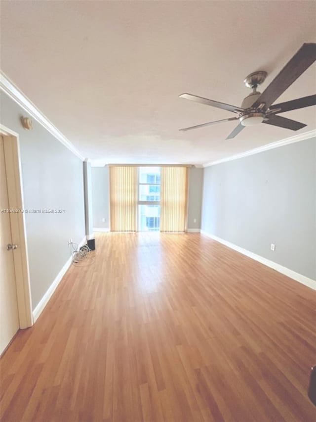 spare room with ornamental molding, a wall of windows, light wood-type flooring, and ceiling fan