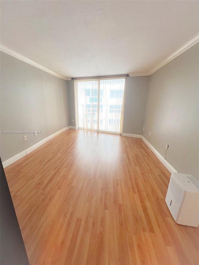 unfurnished room featuring light hardwood / wood-style floors, crown molding, and a wall of windows