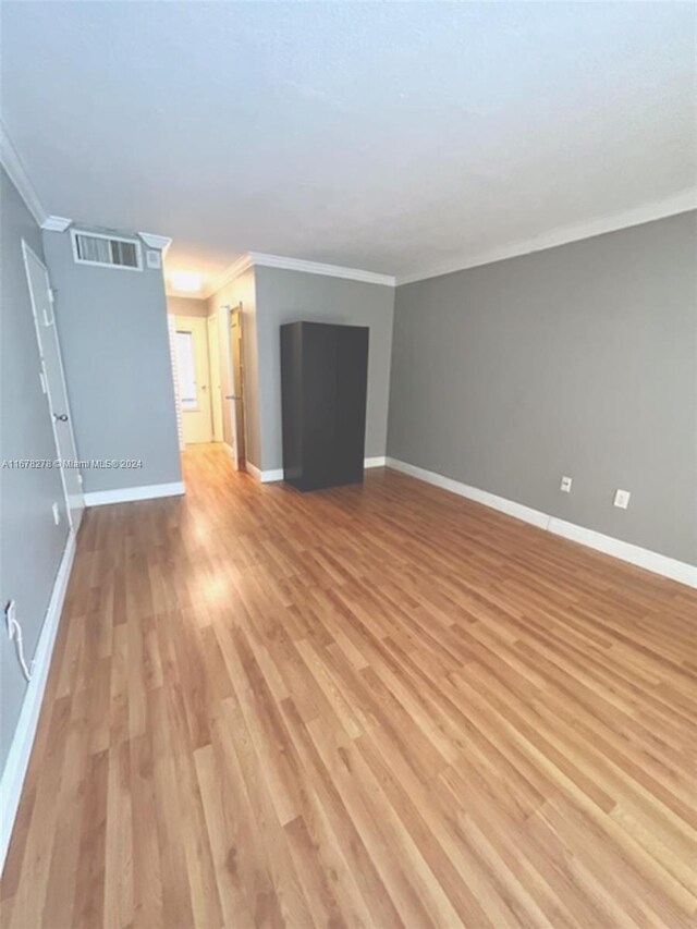 unfurnished living room featuring light hardwood / wood-style floors and ornamental molding