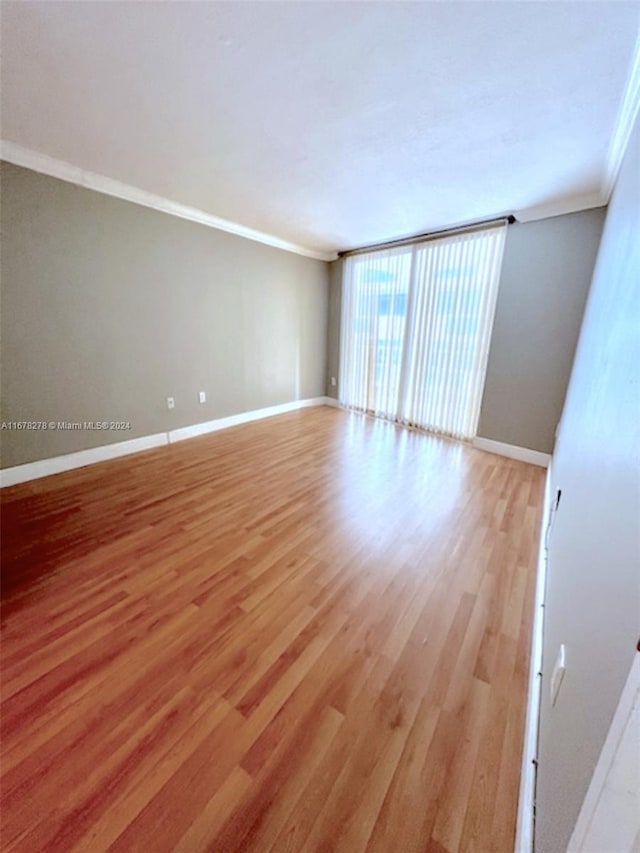 spare room featuring crown molding and light wood-type flooring