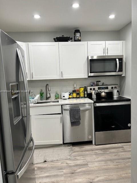 kitchen featuring light hardwood / wood-style flooring, white cabinets, stainless steel appliances, and sink