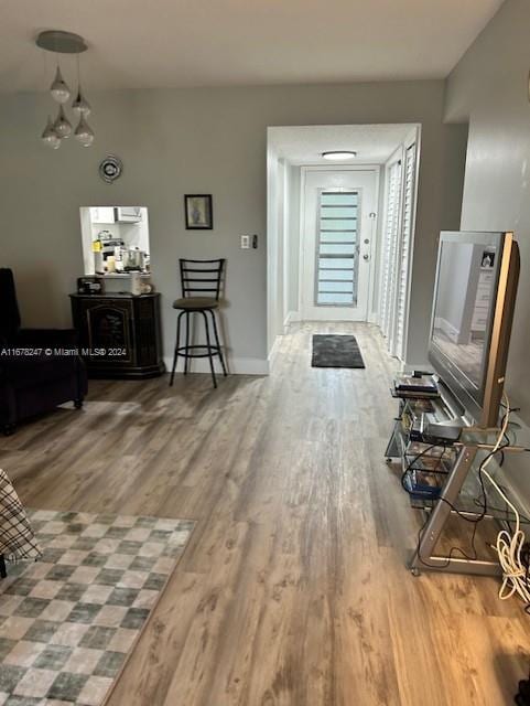 corridor featuring wood-type flooring and an inviting chandelier