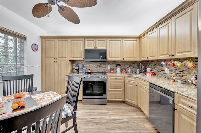 kitchen featuring decorative backsplash, ceiling fan, appliances with stainless steel finishes, light stone countertops, and light wood-type flooring