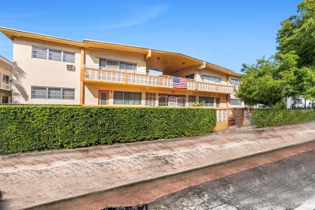 exterior space with fence, a balcony, and stucco siding