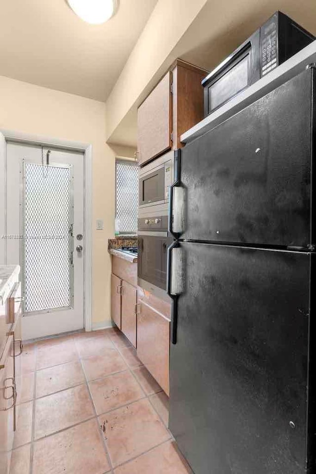 kitchen with light tile patterned floors and stainless steel appliances