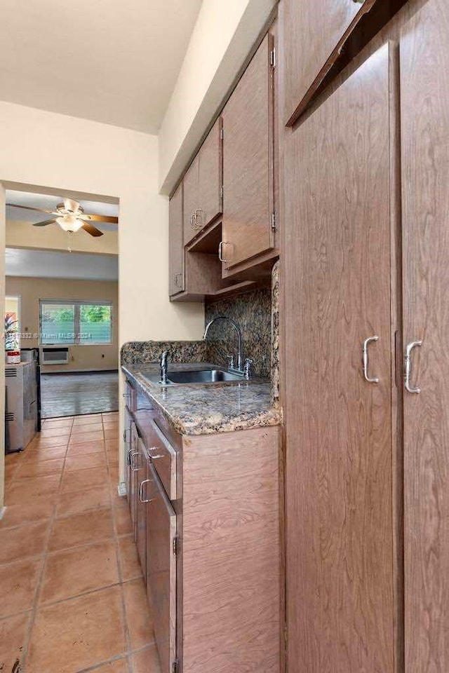 kitchen with ceiling fan, a sink, dark stone countertops, light tile patterned floors, and tasteful backsplash