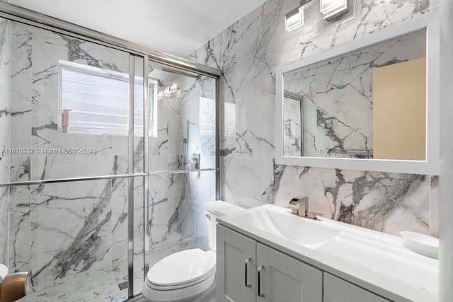 full bathroom with toilet, tile walls, a marble finish shower, and vanity