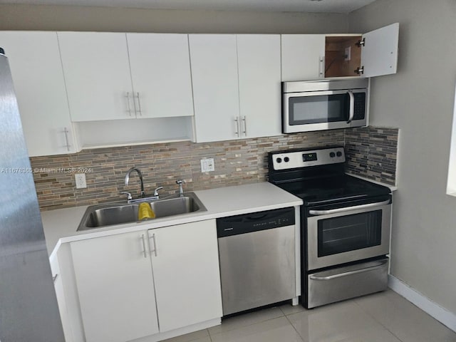 kitchen featuring sink, light tile patterned flooring, white cabinetry, stainless steel appliances, and decorative backsplash