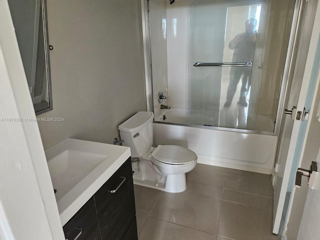 full bathroom featuring bath / shower combo with glass door, toilet, vanity, and tile patterned flooring