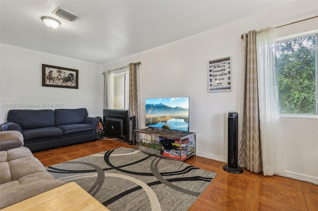 living room with a textured ceiling, tile patterned floors, and a healthy amount of sunlight