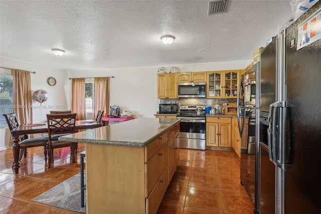 kitchen featuring a kitchen island, a textured ceiling, dark tile patterned flooring, and black appliances