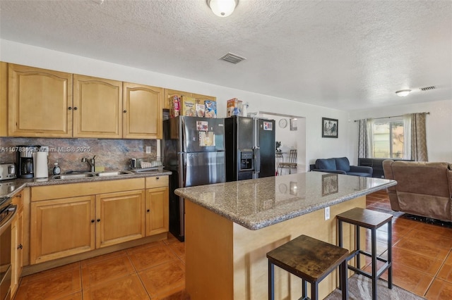 kitchen with sink, a breakfast bar, light stone countertops, and a textured ceiling