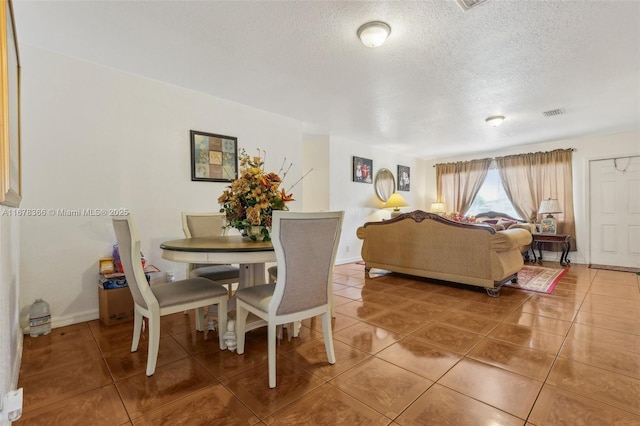 dining space featuring a textured ceiling and tile patterned floors