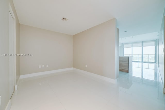 tiled spare room featuring floor to ceiling windows