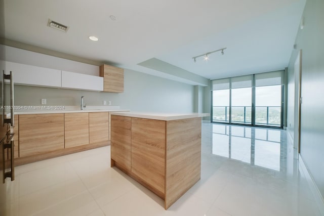 kitchen featuring white cabinets, expansive windows, a kitchen island, and light tile patterned floors