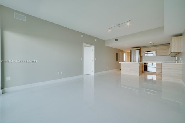 unfurnished living room featuring light tile patterned floors, rail lighting, and sink