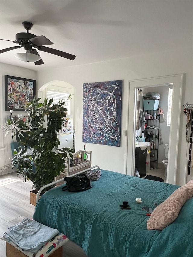 bedroom featuring hardwood / wood-style floors, ceiling fan, and ensuite bath