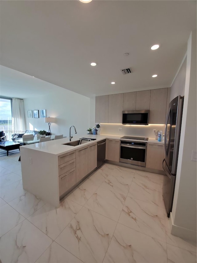 kitchen featuring sink, appliances with stainless steel finishes, kitchen peninsula, and gray cabinetry