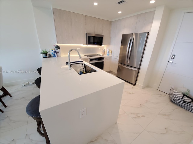 kitchen featuring marble finish floor, recessed lighting, appliances with stainless steel finishes, a sink, and a peninsula