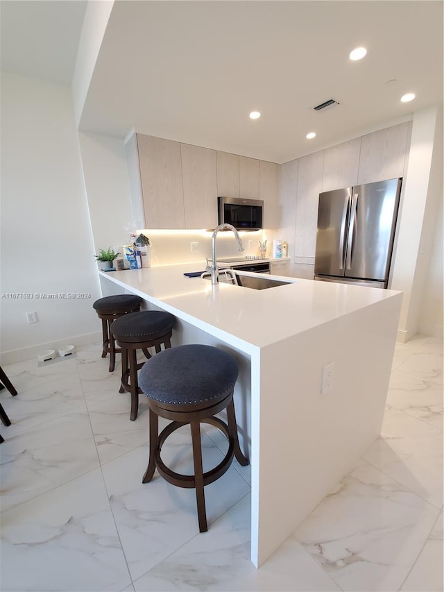 kitchen with a breakfast bar, stainless steel appliances, sink, and kitchen peninsula