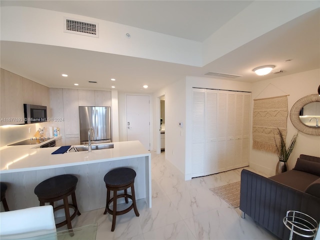 kitchen featuring stainless steel appliances, sink, kitchen peninsula, and a kitchen breakfast bar