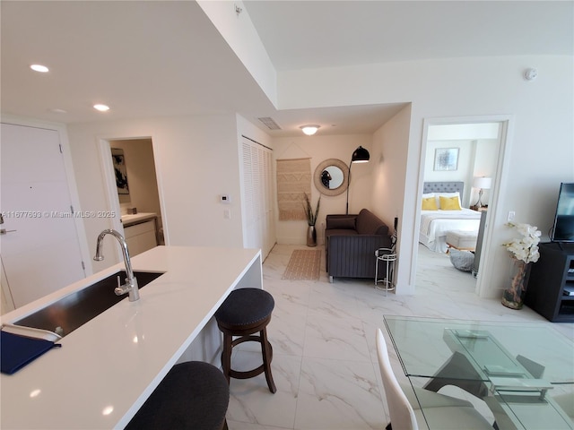 kitchen with visible vents, a breakfast bar, marble finish floor, a sink, and recessed lighting