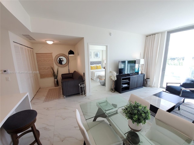 living area featuring marble finish floor, floor to ceiling windows, and visible vents