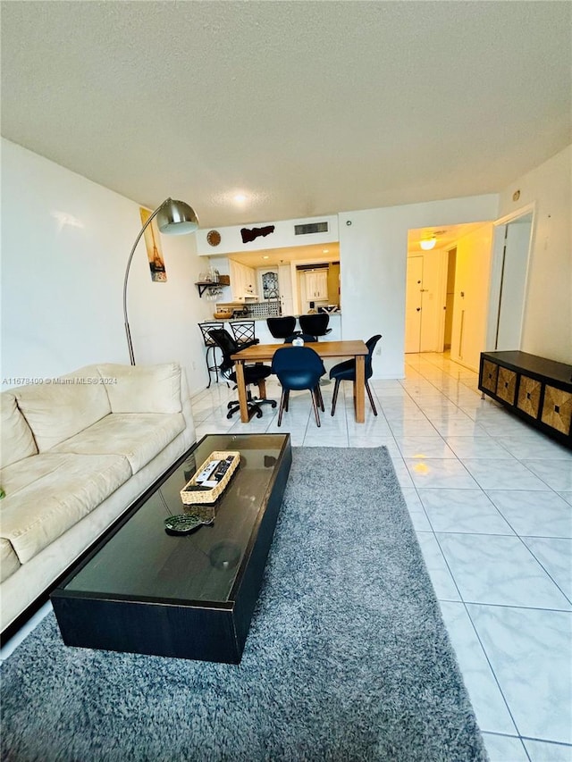 tiled living room featuring a textured ceiling