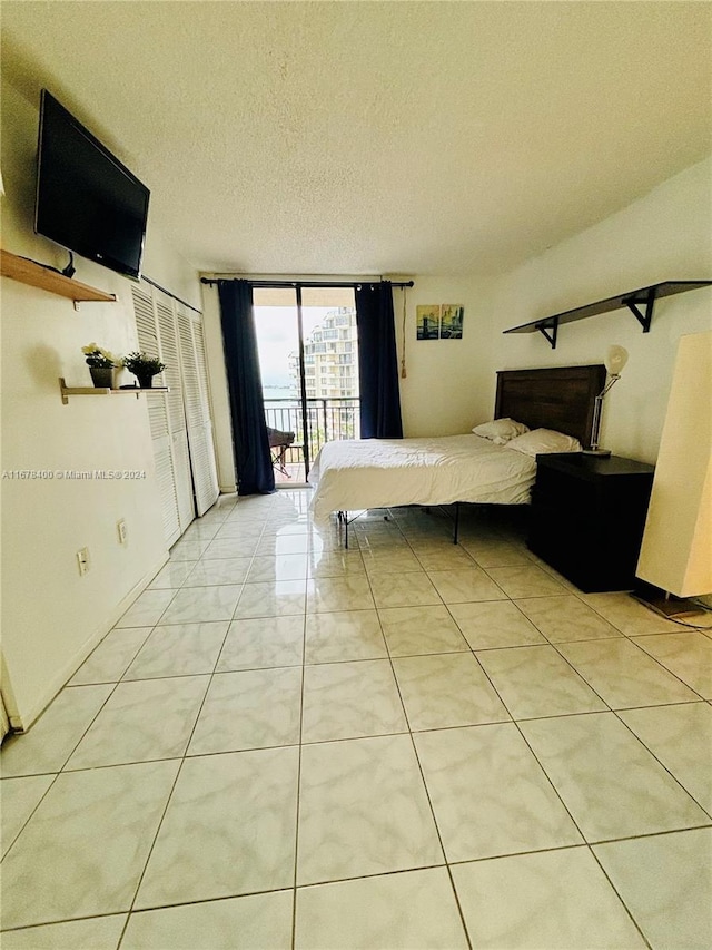 tiled bedroom with a textured ceiling, access to exterior, and floor to ceiling windows