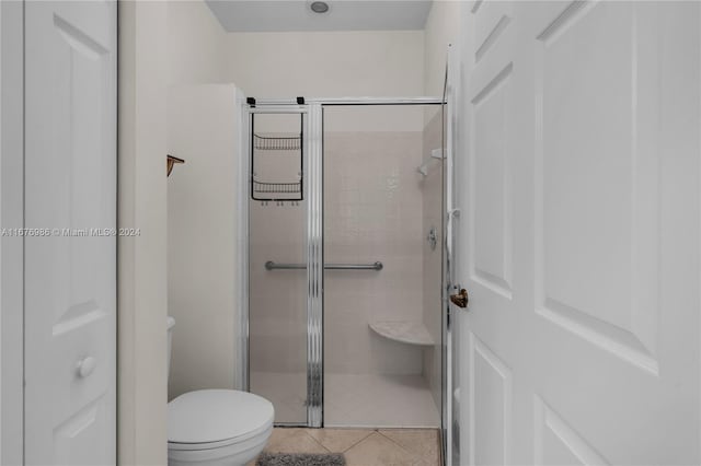 bathroom featuring tile patterned flooring, toilet, and an enclosed shower