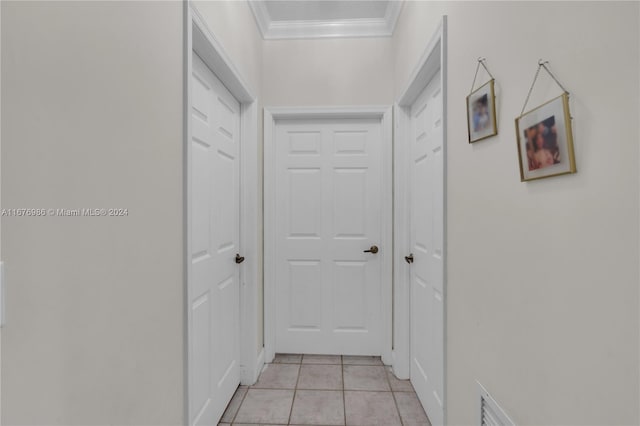 hallway with ornamental molding and light tile patterned floors