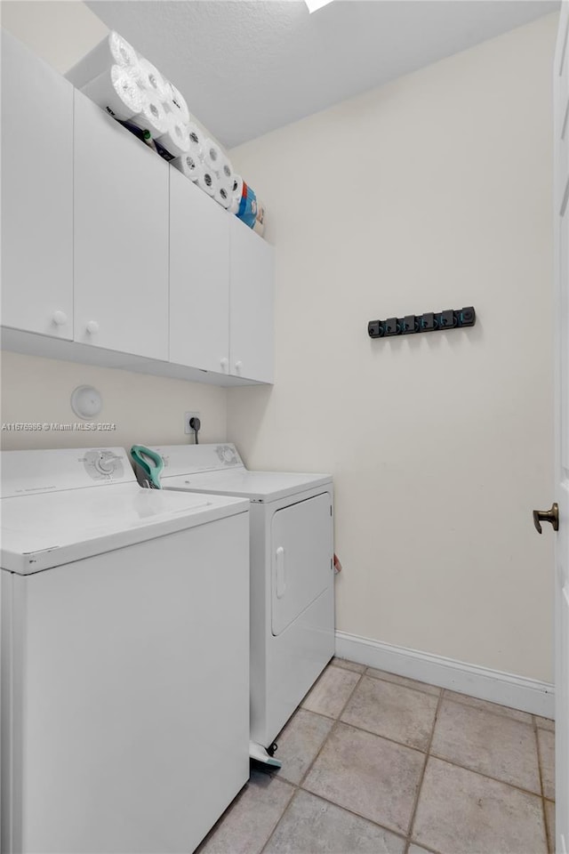 laundry area featuring washer and dryer, light tile patterned floors, and cabinets