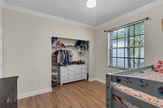 bedroom with a closet, ornamental molding, and light hardwood / wood-style flooring