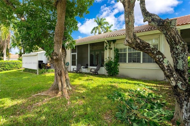 rear view of house featuring a lawn and a sunroom